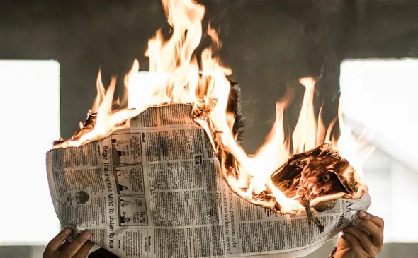 person med brinnande tidning, symboliserar heta nyheter.