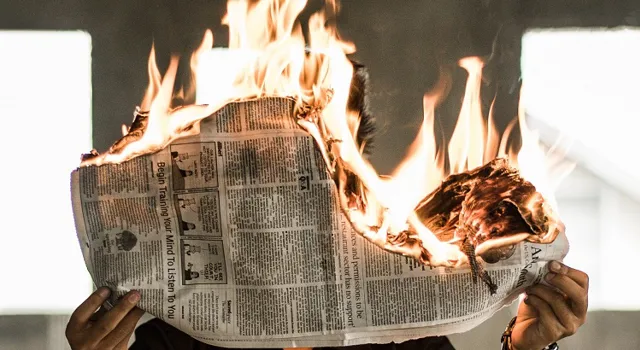 person med brinnande tidning, symboliserar heta nyheter.